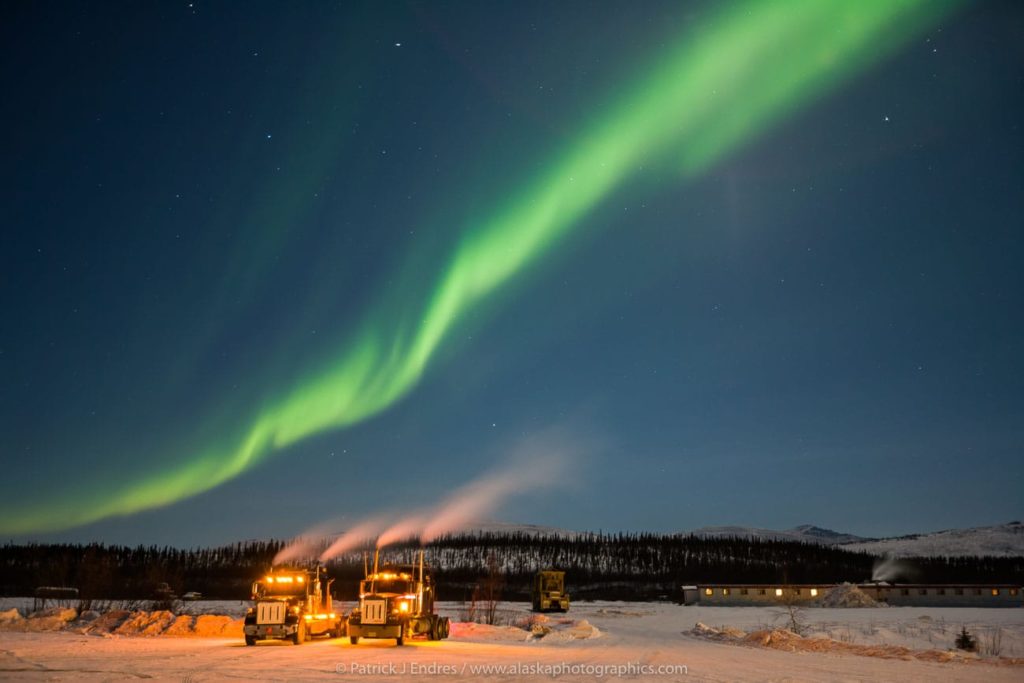 Aurora streams over Semi tractor trailer trucks at the Coldfoot truckstop in Coldfoot, Alaska.